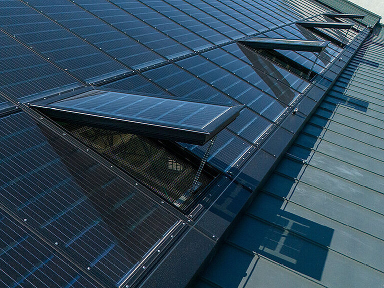 Glasdach auf geneigtem Metalldach mit integrierten Glasflächen und Rahmenkonstruktion, Ansicht von oben im urbanen Umfeld