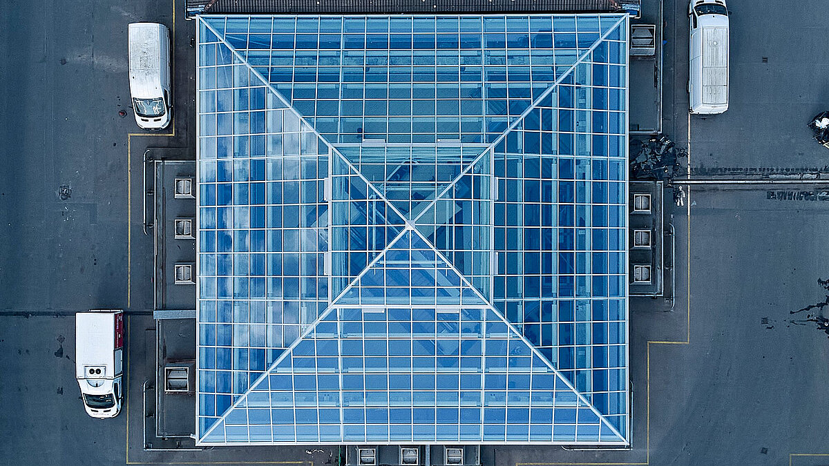 Luftaufnahme eines quadratischen Glasdachs mit Stahlrahmen auf einem Flachdachgebäude