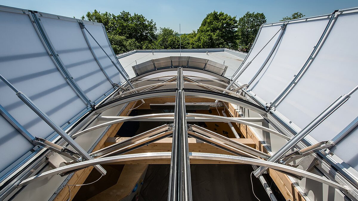 Detailaufnahme des geöffneten gewölbten Glasdachs im Kletterzentrum OWL, mit sichtbarer Metallkonstruktion und Tageslichteinfall.