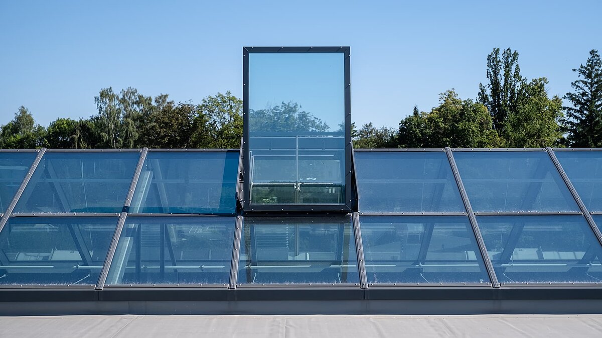Glasdach mit Flachdach-Ausstieg beim Outlet Center Selb, umgeben von Bäumen.