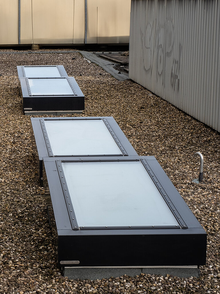 Mehrere LAMILUX Brandschutzfenster auf Kies-Flachdach vor Fassadenwand