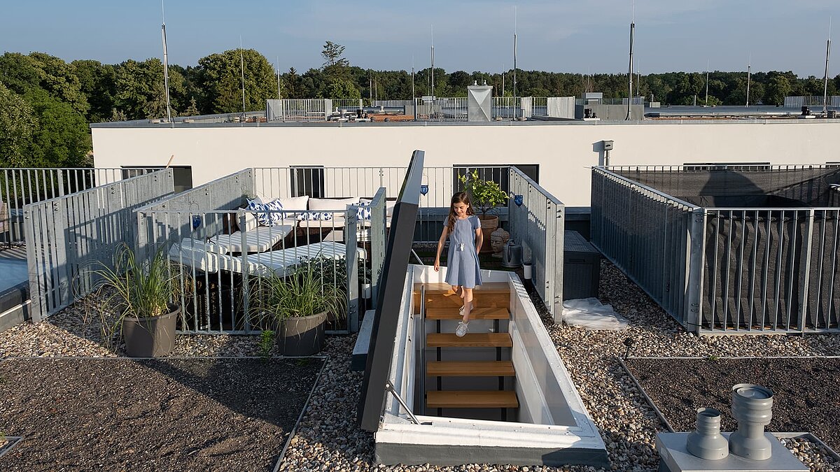 Girl climbing through a flat roof exit onto the private rooftop terrace of a Townhouse in Berlin.