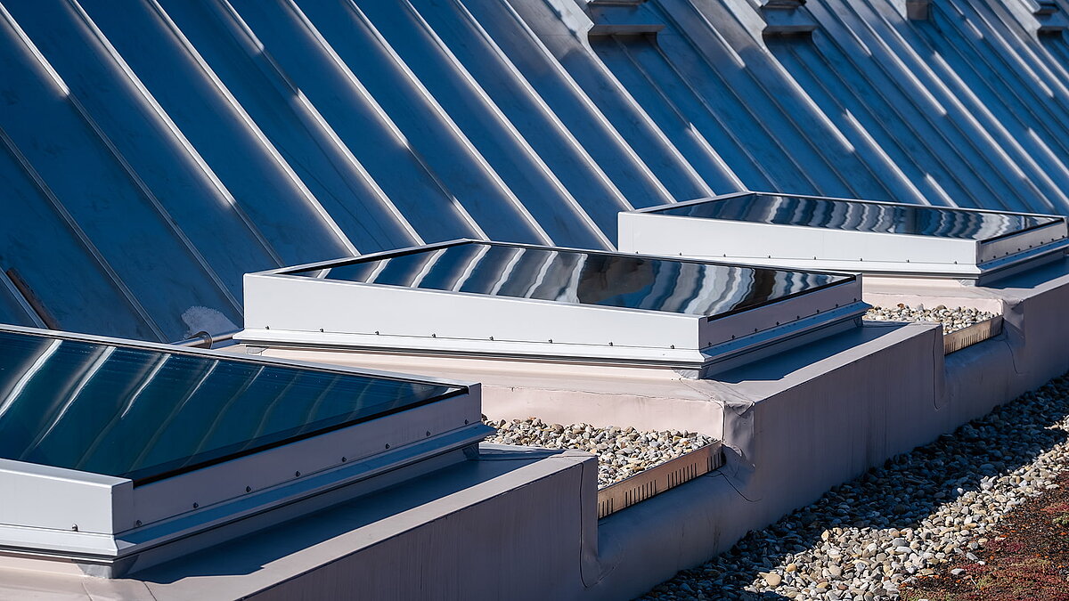 Flachdach der Kinderkrippe Waltenhofen mit modernen, rechteckigen Oberlichtern für Tageslichteinfall.