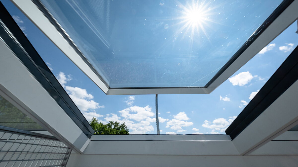 Wohnhaus in Freiburg mit modularen Glasdach von LAMILUX, Blick durch das geöffnete Dach in den Himmel.