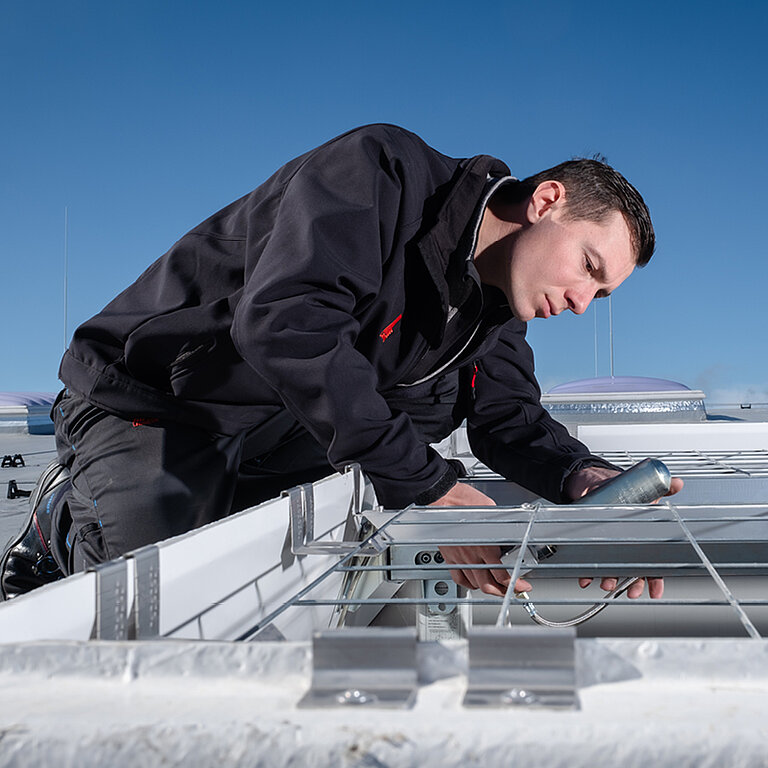Handwerker montiert ein Tageslichtelement auf einem Flachdach