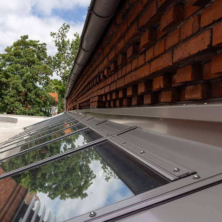 Glasdach Fire Resistance mit reflektierender Verglasung an Ziegelfassade.