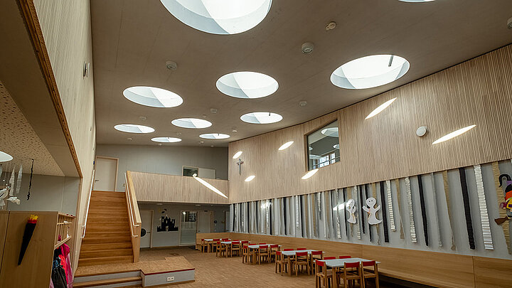 Mehrzweckraum des Kindergartens St. Severin in Garching mit runden Flachdach Fenstern Lichtspiel der runden Flachdach Fenster im Aufenthaltsraum eines Kindergartens | insights by LAMILUX