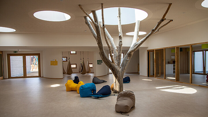 Innenbereich der LamiKita mit Baum und Glasdach | insights by LAMILUX