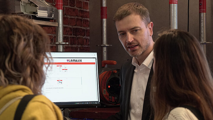 Carsten Ficker Leiter LAMILUX Academy auf digitalBAU mit zwei Messestandsbesucherinnen | insights by LAMILUX