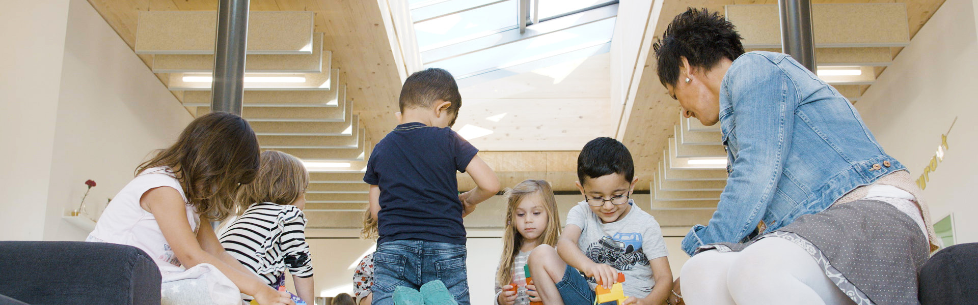 Kindergartenkinder spielen unter dem Glasdach der BRK Kita in Hof Kindgerechte Atmosphäre mit LAMILUX Glasdach PR60 in der BRK Kita in Hof | insights by LAMILUX