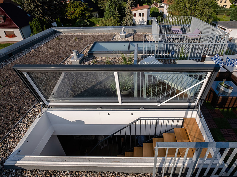 Flachdach-Ausstieg auf moderne Dachterrasse mit Pflanzen und Sitzmöbeln