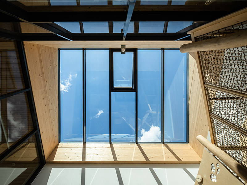 Blick nach oben durch ein modernes Glasdach mit blauem Himmel.