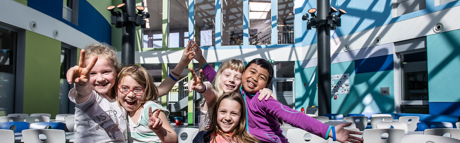Schülerinnen im Lichthof der International School Bonn Glasdach von LAMILUX auf Baumkonstruktion aus Stahl von Mirotec | insights by LAMILUX