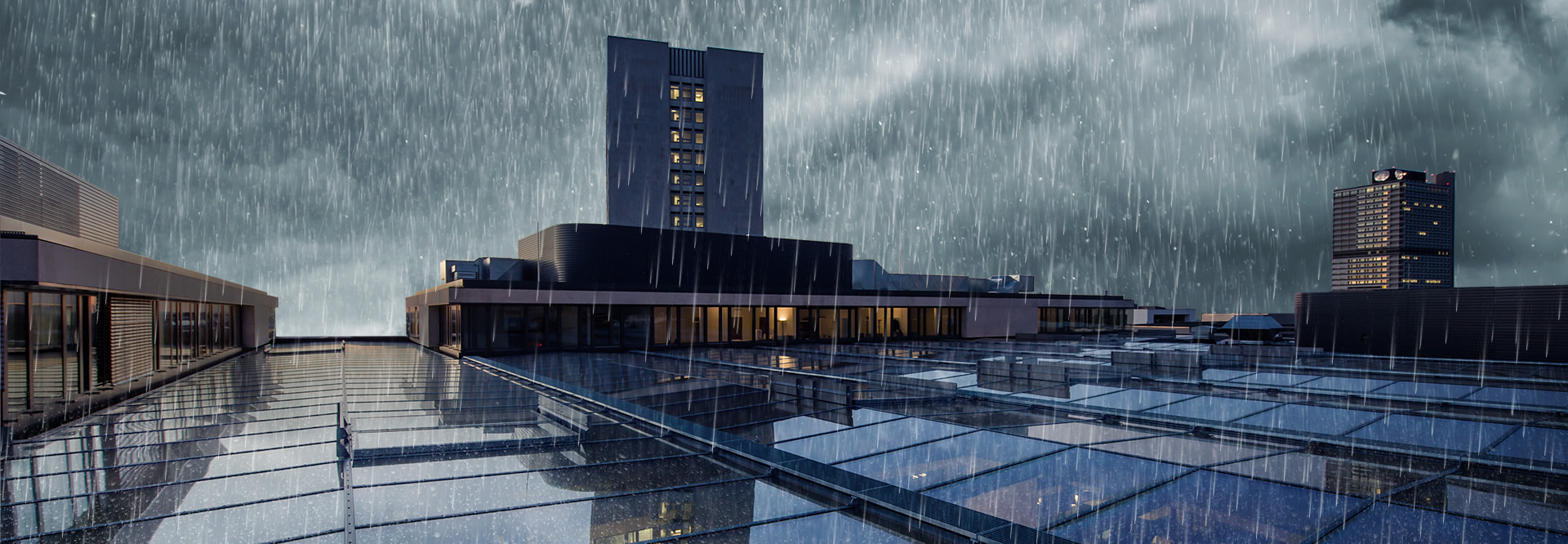 LAMILUX Glasdach PR60 als großflächiges Glasdachsystem auf Gebäude im urbanen Umfeld, dargestellt bei Regen und widrigen Wetterbedingungen