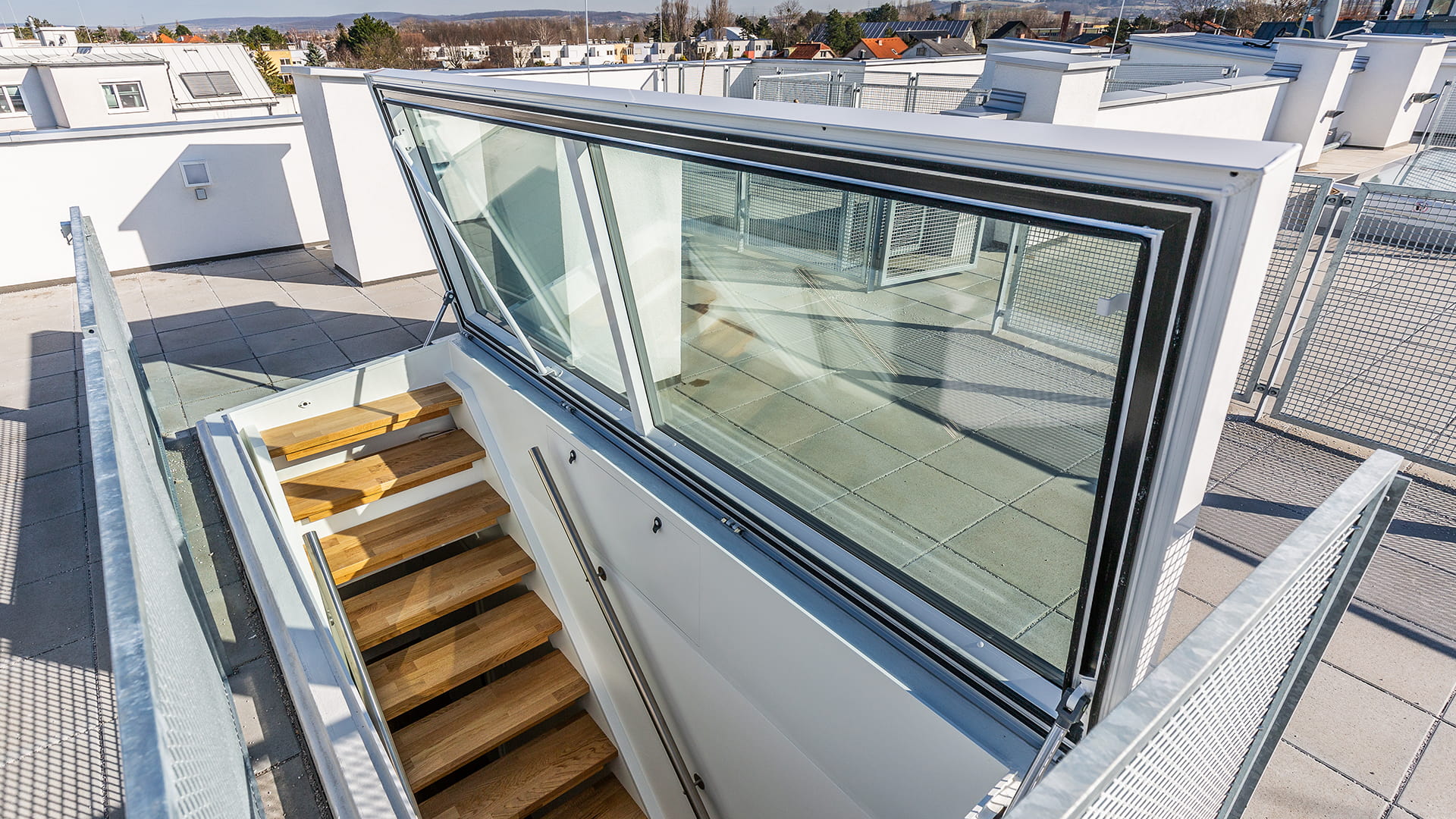 Flachdach Ausstieg von LAMILUX bei einem Wohnhaus in Korneuburg, moderne Treppe und Verglasung mit Ausblick auf die Umgebung.
