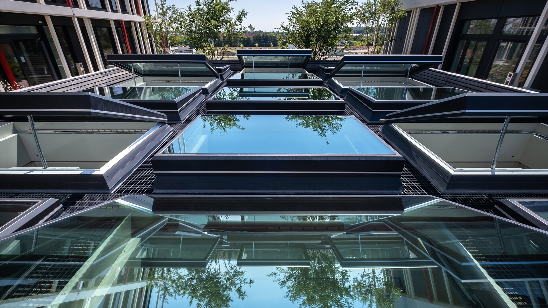Perspektivische Ansicht eines modernen Glasdachs mit schwarzen Kunststoffrahmen und Spiegelungen eines Bürogebäudes