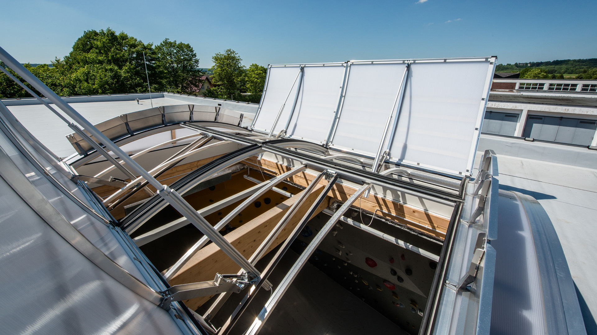 Geöffnete RWA-Fenster in Dachverglasung über Atrium mit sichtbarer Tragkonstruktion zur Rauch- und Wärmeabführung